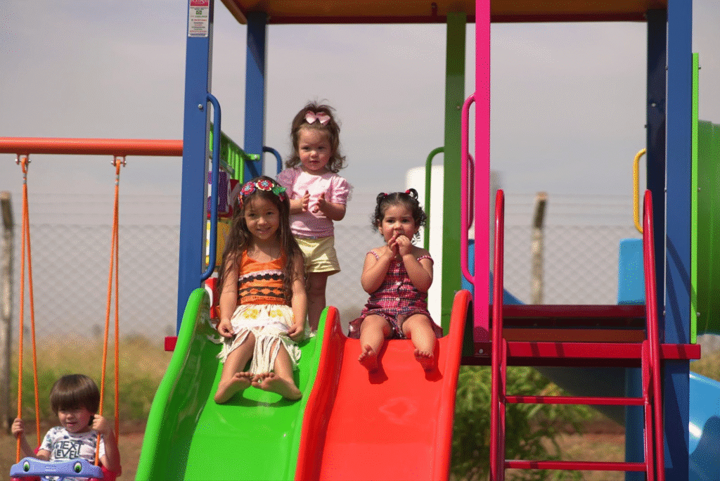 Crianças brincando em escorregador de parque infantil ao ar livre, diversão e alegria entre amigos